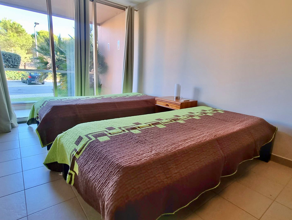 Comfortable twin bedroom with closet, air conditioning, and balcony of Luxury T3 Apartment at Salgados Vila das Lagoas