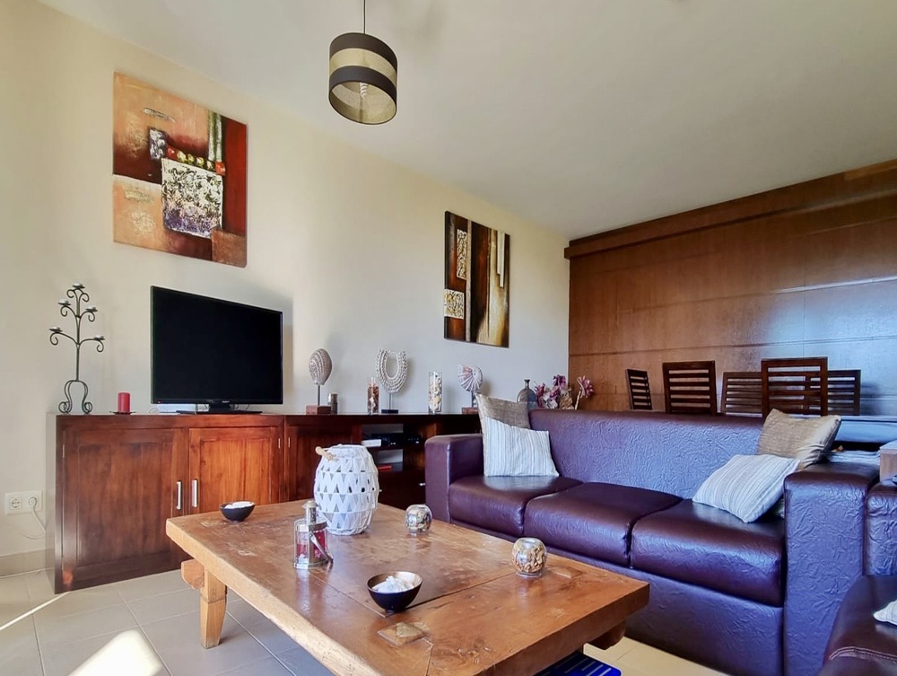 Sala de jantar e de estar espaçosa com sofá grande e televisão em Apartamento T3 de Luxo em Salgados Vila das Lagoas, Albufeira